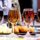 Defocussed brunette tasting different kind of wine standing on table with snacks outdoors